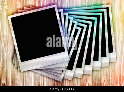 Abbildung von einem Haufen von Sofortbildfilm Fotos in einer Reihe auf einem Holztisch mit einem Regenbogen-Grunge-Effekt angeordnet. Stockfoto