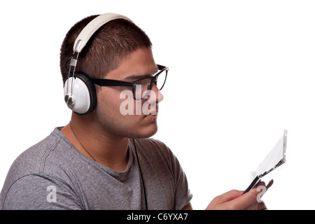 Ein junger Mann hört Musik mit Kopfhörern während der Prüfung der Album-cd-Hülle. Stockfoto