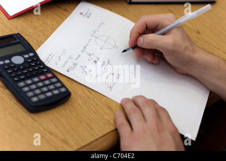 Ein junger Mann, mathematische Gleichungen auf Papier arbeiten. Stockfoto