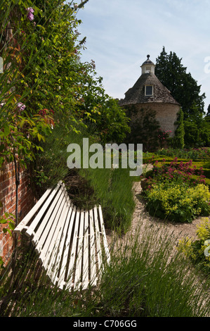 Eine stilvolle Gartenbank im Parterre Rousham Haus mit der ursprünglichen Taubenschlag darüber hinaus, Oxfordshire, England Stockfoto