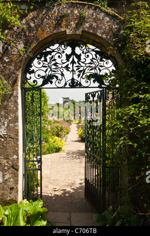 Ein reich verzierten schmiedeeisernen Tor inmitten einer Cotswold Steinbogen in der ummauerten Garten Rousham House in Oxfordshire, England öffnet Stockfoto