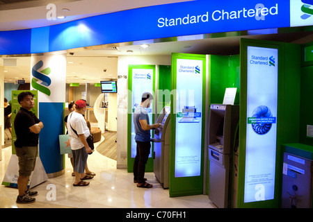 Leute, die Geld von einem Standard Chartered Bank ATM in Singapur Asien Stockfoto