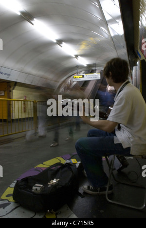 Straßenmusiker auf Londoner Underground Musik zu spielen, wie Menschen, London, UK vorbeigehen Stockfoto