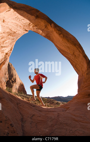 Barfuß männliche Läufer unter Sandstein Bogen, Moab, Utah. Stockfoto