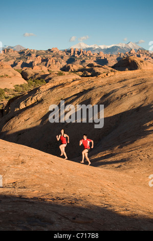 Mann und Frau barfuß laufen auf Sandstein über den Colorado River, Moab, Utah. Stockfoto