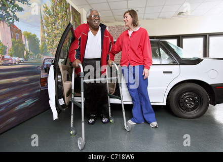 Ein Physiotherapeut arbeitet mit einem Patienten wie man in und aus einem Auto. Stockfoto