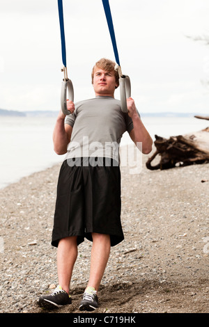 Ein Mann nutzt Aussetzung Ringe an einem Strand. Stockfoto