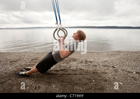 Ein Mann nutzt Aussetzung Ringe an einem Strand. Stockfoto