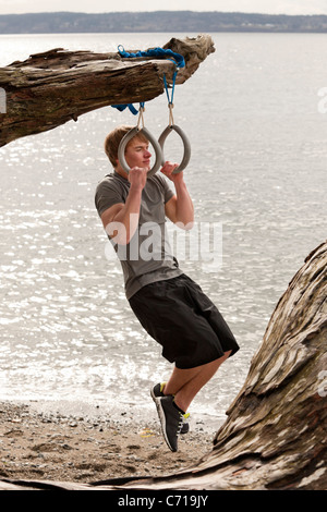 Ein Mann nutzt Aussetzung Ringe an einem Strand. Stockfoto