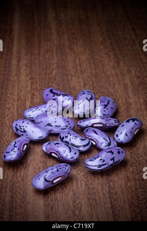 Scarlet Stangenbohnen (Phaseolus Coccineus), fotografiert im Studio auf einem exotischen Holz Brett. Fèves de Gartenbohnen d' Espagne. Stockfoto