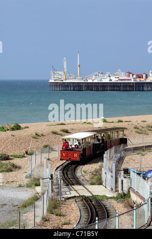 Ein Zug auf der Volks-Bahn schlängelt sich um eine doppelte Biegung mit Brighton Pier im Hintergrund. Stockfoto