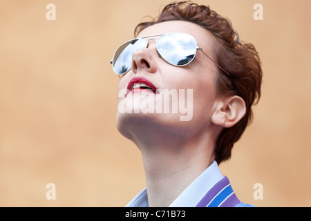 HighRes Kopfschuss von modernen Reife Frau mit Sonnenbrille mit Neugier nachschlagen. Rote Lippen im Fokus Stockfoto