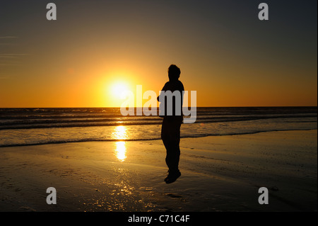 Mann springt am Strand während eine gelbe Sonnenuntergang über dem Atlantik von la Côte Sauvage, Charente Maritime, Frankreich Stockfoto