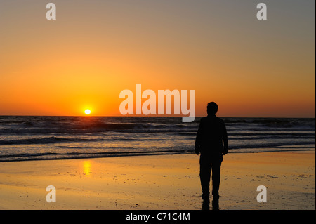 Mann zu Fuß am Strand eine gelbe Sonnenuntergang über Atlantik von la Côte Sauvage, Charente Maritime, Frankreich Stockfoto
