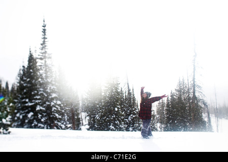 Eine schöne Frauen Lächeln beim Wandern durch unberührte Schneefeld bei Sonnenuntergang in Wyoming. Stockfoto