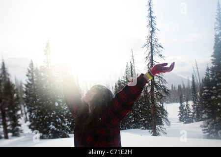 Eine schöne Frauen Lächeln beim Wandern durch unberührte Schneefeld bei Sonnenuntergang in Wyoming. Stockfoto