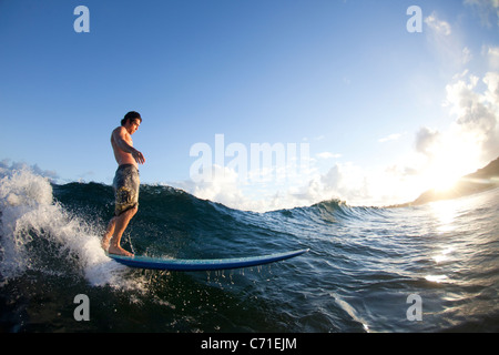 Ein junger Mann in das Licht am Monster Brei auf der Nordküste von Oahu, Hawaii surfen. Stockfoto