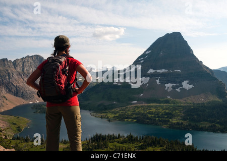 Eine junge weibliche Wanderer blickt auf verborgenen See und Bear Hut Mountain im Glacier National Park, Montana. Stockfoto