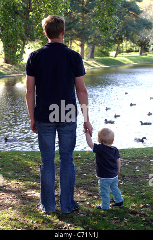 Vater und Sohn beobachten Enten auf dem Teich Stockfoto