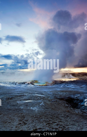 Die Clepsydra Geyser bricht bei Sonnenuntergang im unteren Geysir Becken des Yellowstone National Park, Wyoming. Stockfoto