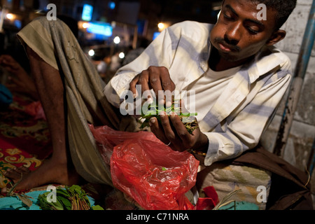 Ein Mann kaut und vertreibt Khat (Qat) in der Nacht Khat Markt in Aden, Jemen. Stockfoto