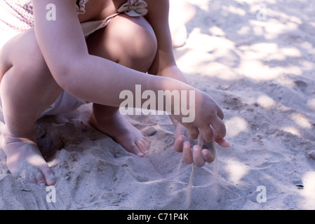 Kleines Mädchen läuft Sand durch Hände, niedrige Abschnitt Stockfoto