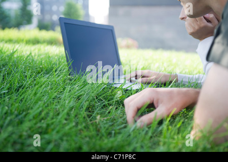 Menschen mit Laptop-Computer im liegen auf dem Rasen, beschnitten Stockfoto