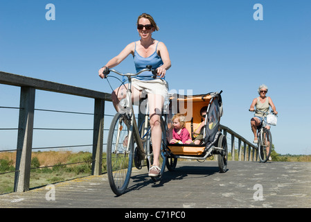 Mehr-Generationen-Familie genießen Fahrradtour, Kinder sitzen in Fahrradanhänger Stockfoto