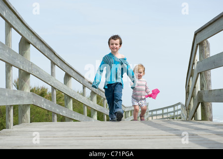 Junge Geschwister gehen Hand in Hand auf Promenade Stockfoto