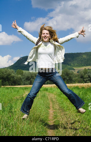 Frau springen vor Freude auf einer Wiese Stockfoto