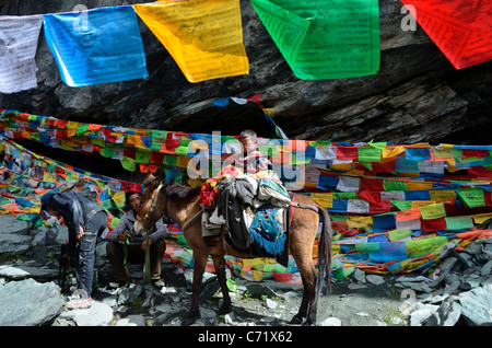 Eine tibetische Familie eine Pause auf dem felsigen Pfad. Daocheng, Sichuan, China. Stockfoto