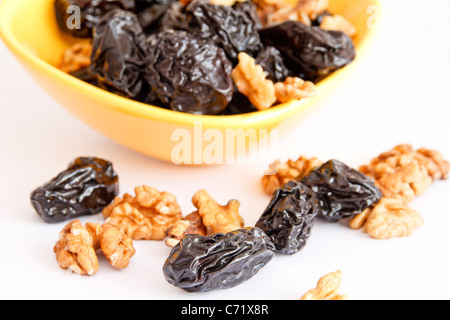 Pflaumen mit Nüssen in Schüssel auf weißem Hintergrund Stockfoto