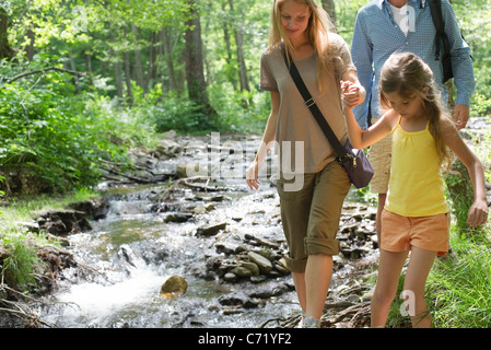 Familie zu Fuß neben Bach im Wald Stockfoto