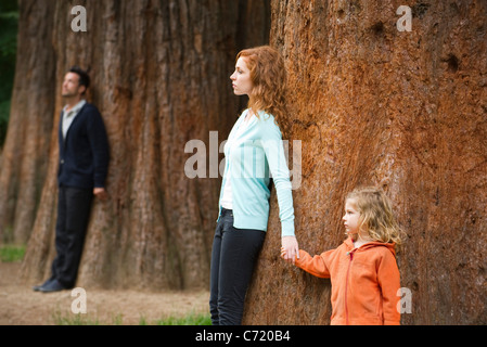 Mutter und Tochter lehnte sich gegen Baum, Vater steht trennen im Hintergrund Stockfoto