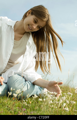 Junge Frau sitzt auf der Wiese mit Wildblumen Stockfoto