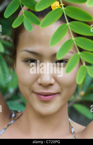 Junge Frau hinter Blättern Stockfoto
