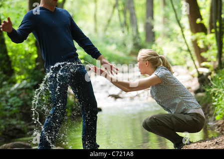 Junge Frau Spritzwasser bei man Stockfoto