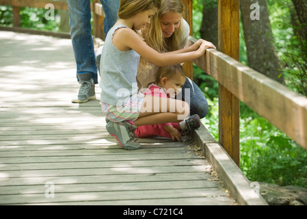 Mutter und zwei Töchter, die mit Blick auf das Geländer der Brücke zusammen Stockfoto