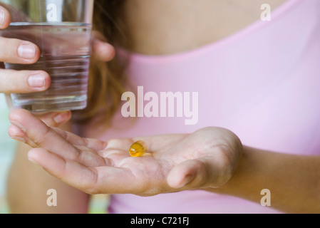 Junge Frau mit Vitamin-Pille und ein Glas Wasser, beschnitten Stockfoto