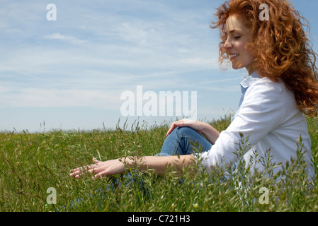 Frau sitzt auf Wiese, Rasen Finger durchlaufen Stockfoto