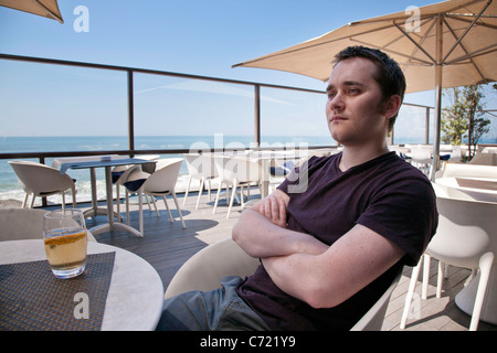 Junger Mann sitzt in einem Café am Foz do Douro Stockfoto