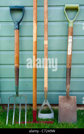 Garten / Gartenarbeit Werkzeuge lehnt sich an die Seite der ein Gartenhaus - einschließlich einer Gabel, Rechen, Hacke und Spaten verwendet. Stockfoto