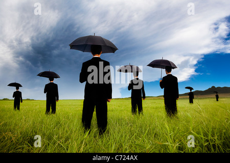 Kaufmann im schwarzen Anzug hält Regenschirm und beobachten der Sturm kommt Stockfoto