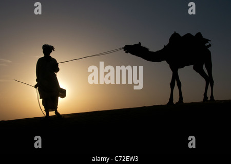 Silhouette Mensch und Kamel bei Sonnenuntergang Sam Dünen Desert National Park westlichen Rajasthan Indien Stockfoto