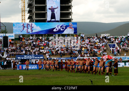 Mongolischen Ringkämpfer, die die traditionellen Garuda Tanz, "Bogenschießen" Schild im Hintergrund, NAADAM Festival, Ulaanbaatar, Mongolei. © kraig Lieb Stockfoto