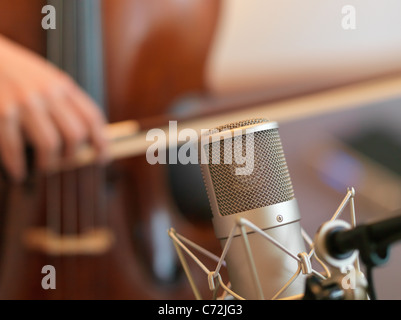 Cello mit einem Neumann d-01 digitale Mikrofon aufzeichnen. Cello mit dem Bogen im Hintergrund unscharf. Stockfoto