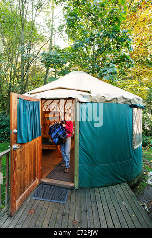 Frau, die Campingausrüstung durch Tür Vermietung Jurte Kajak Point County Park, Snohomish County, Washington, USA Stockfoto