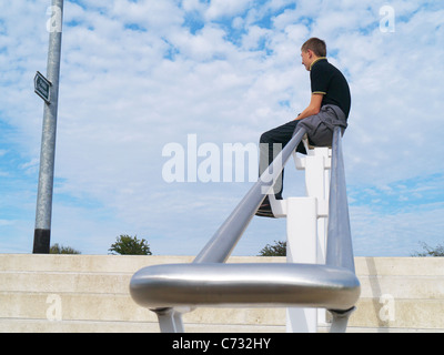 Junge saß und sah bei einem Wegweiser Stockfoto