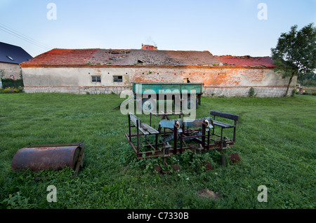 Bild von einer alten, rostig, landwirtschaftliche Geräte, Anhänger und ein altes Gebäude Stockfoto