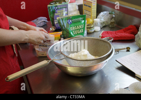 Eine Person, mischen und sieben Zutaten für Kuchen. Stockfoto